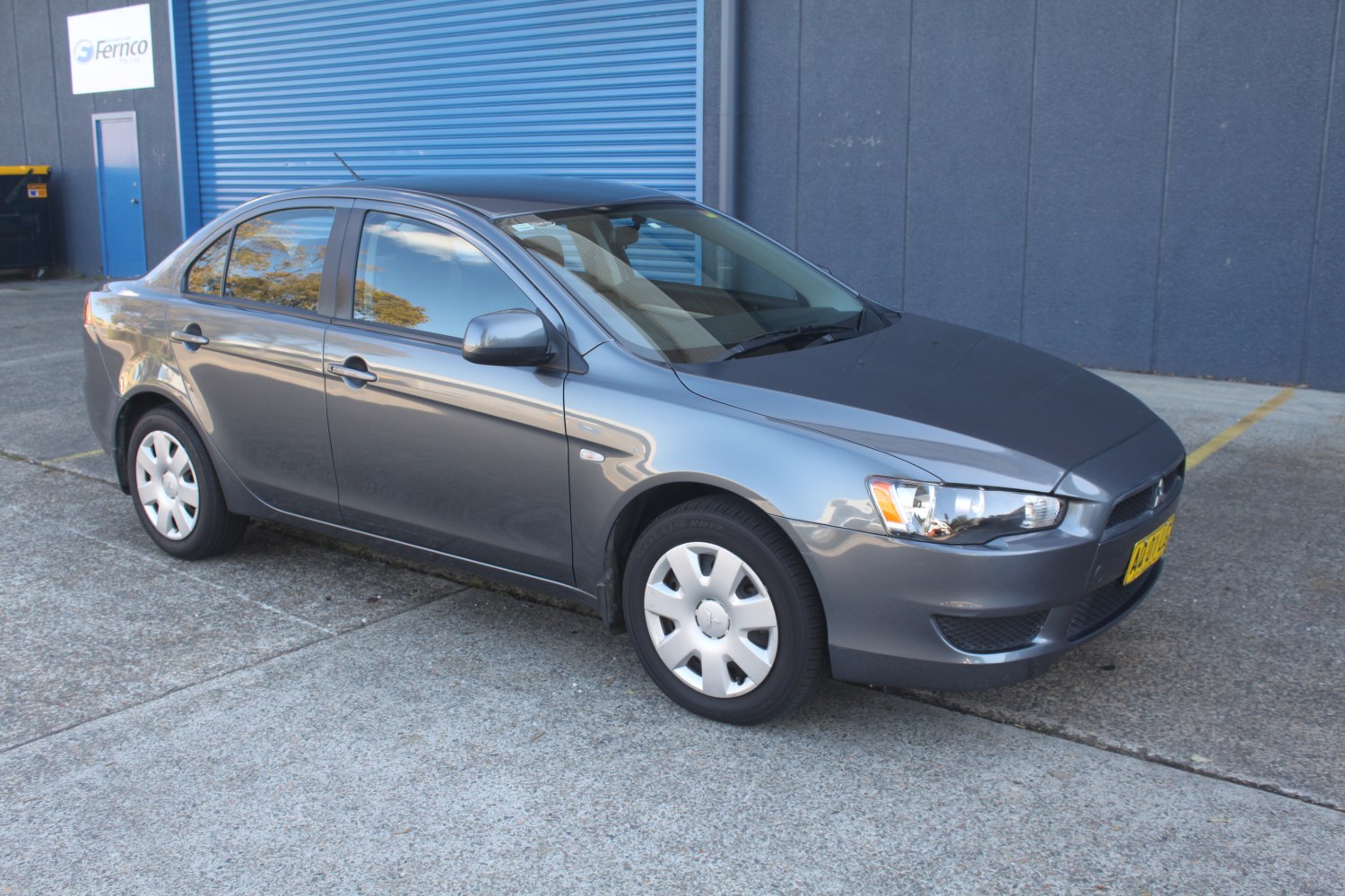 Compact sedan front side with gray paint and wheel covers