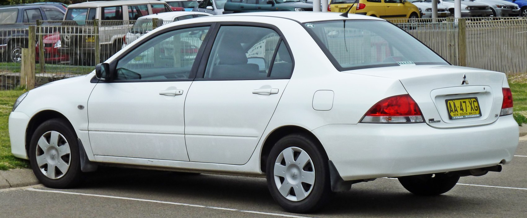 White sedan rear side view with classic four-door design and red tail lights
