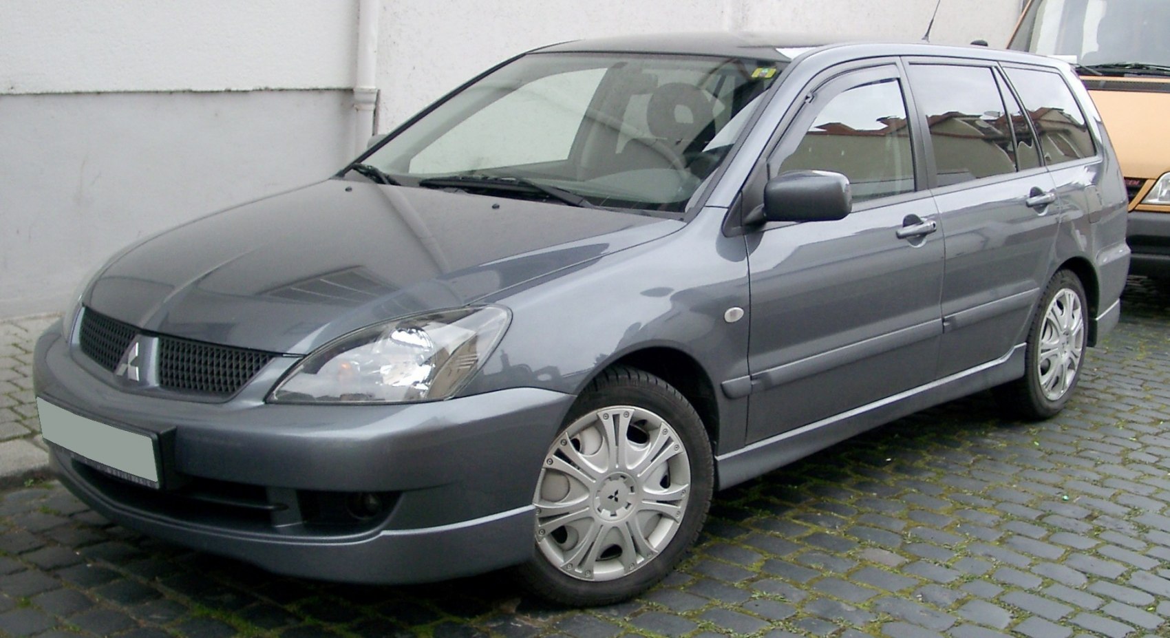 Front side view of a gray wagon with distinctive headlight and grille.