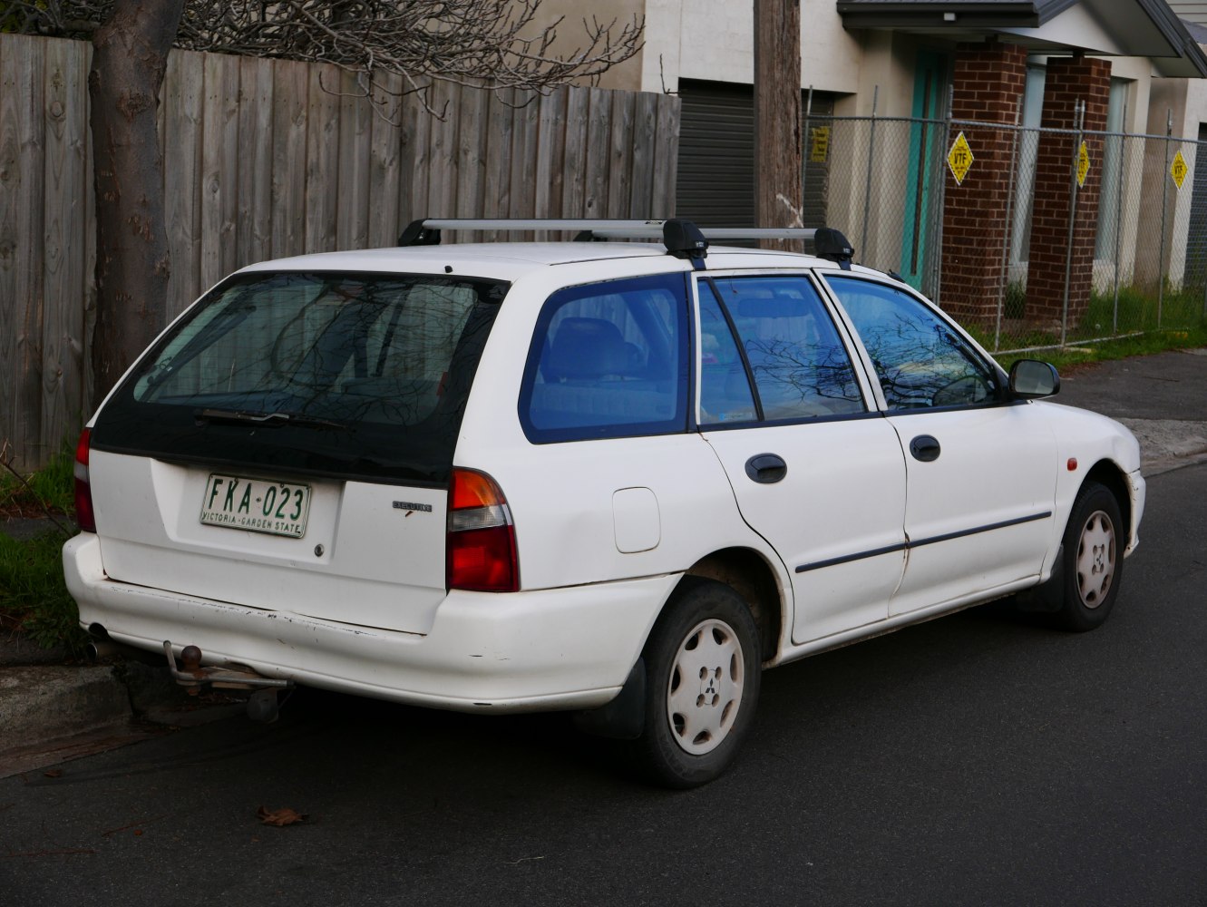 White station wagon with roof bars and tow hitch from 1990s