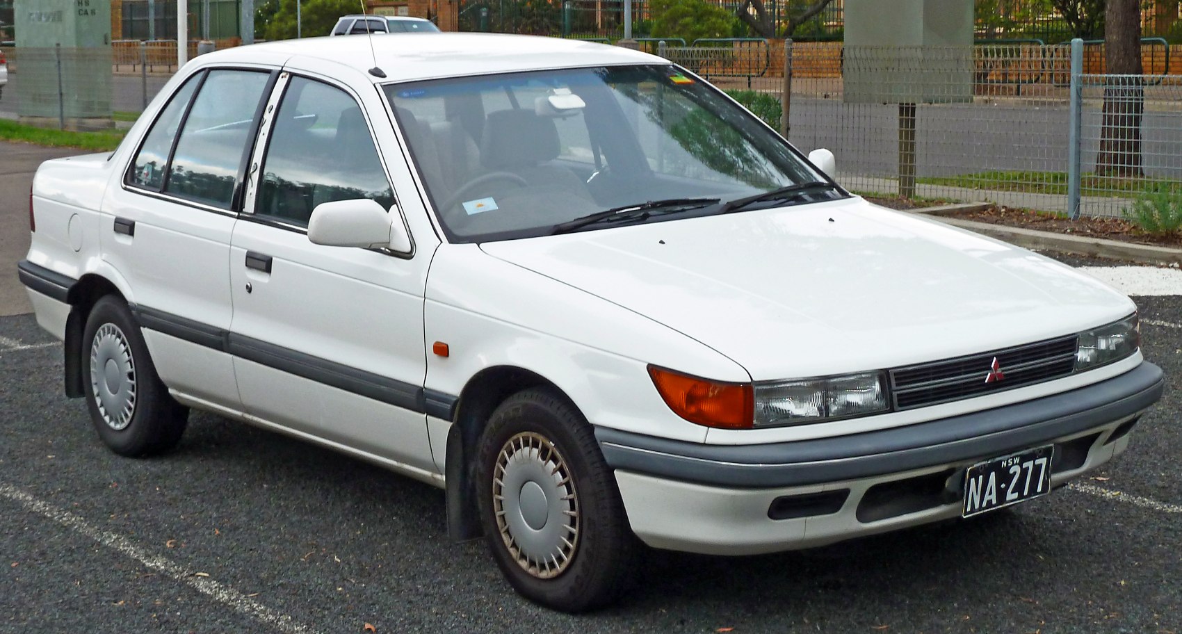 White four-door sedan with original hubcaps and front side view