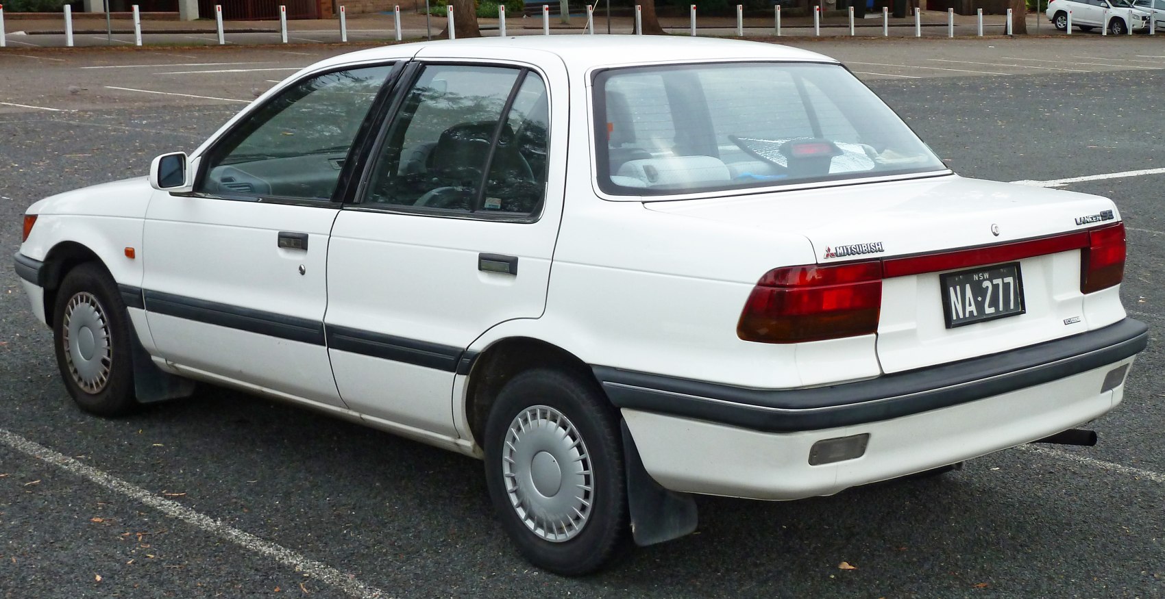 Rear side view of a sedan with rectangular taillights and vintage hubcaps