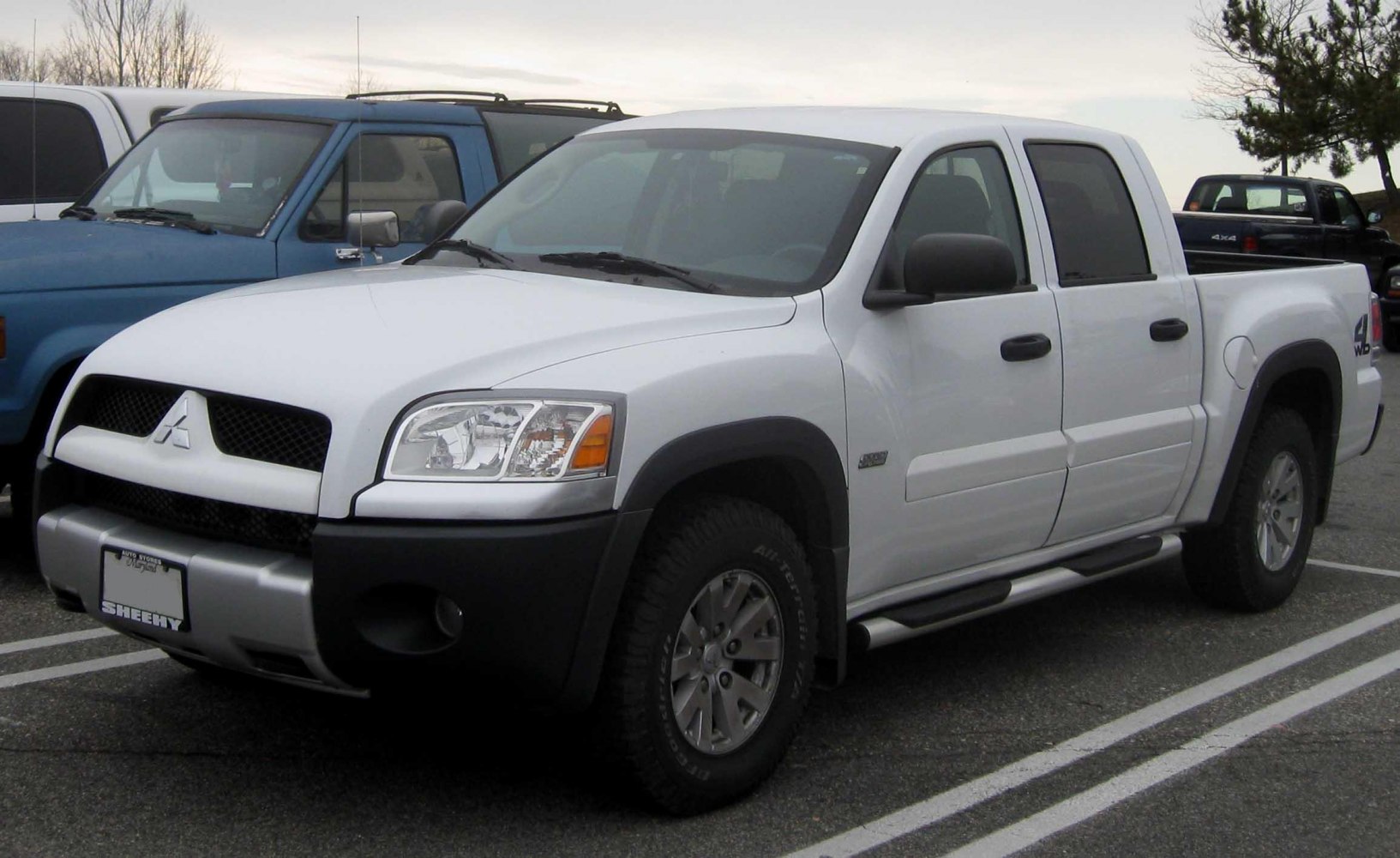 White crew cab pickup with black front bumper and off-road tires