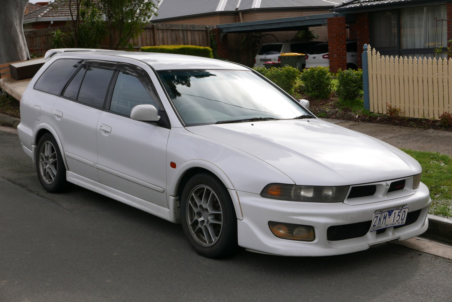 White station wagon front-side view with headlights and alloy wheels