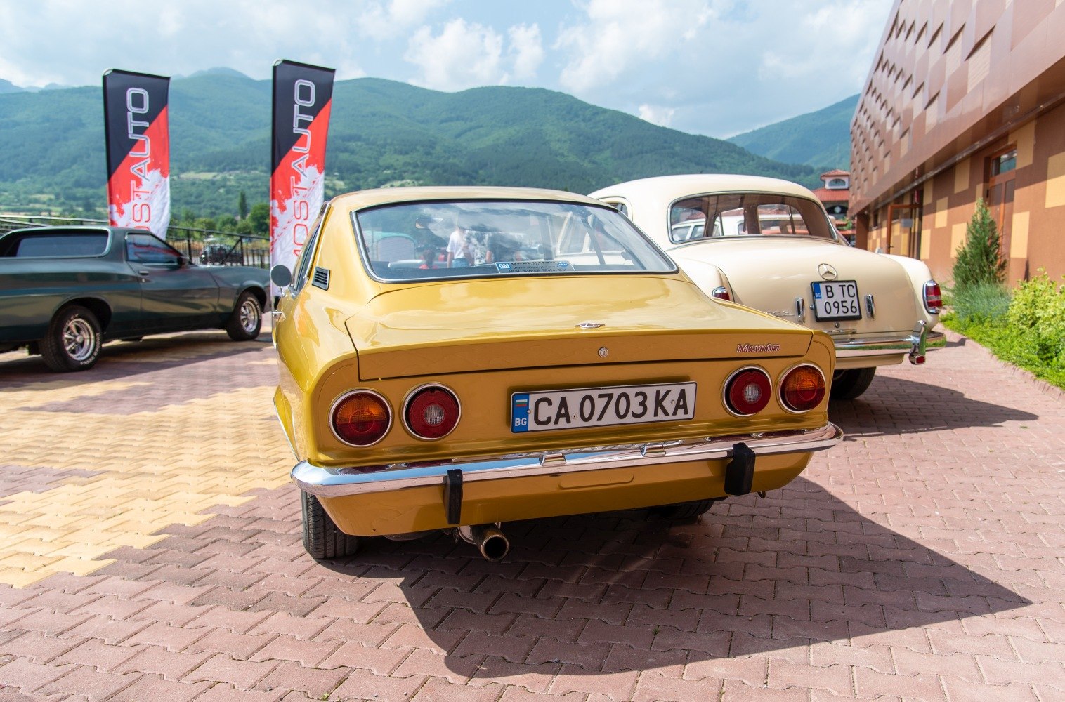 Rear view of a yellow classic coupe with round taillights and chrome bumper