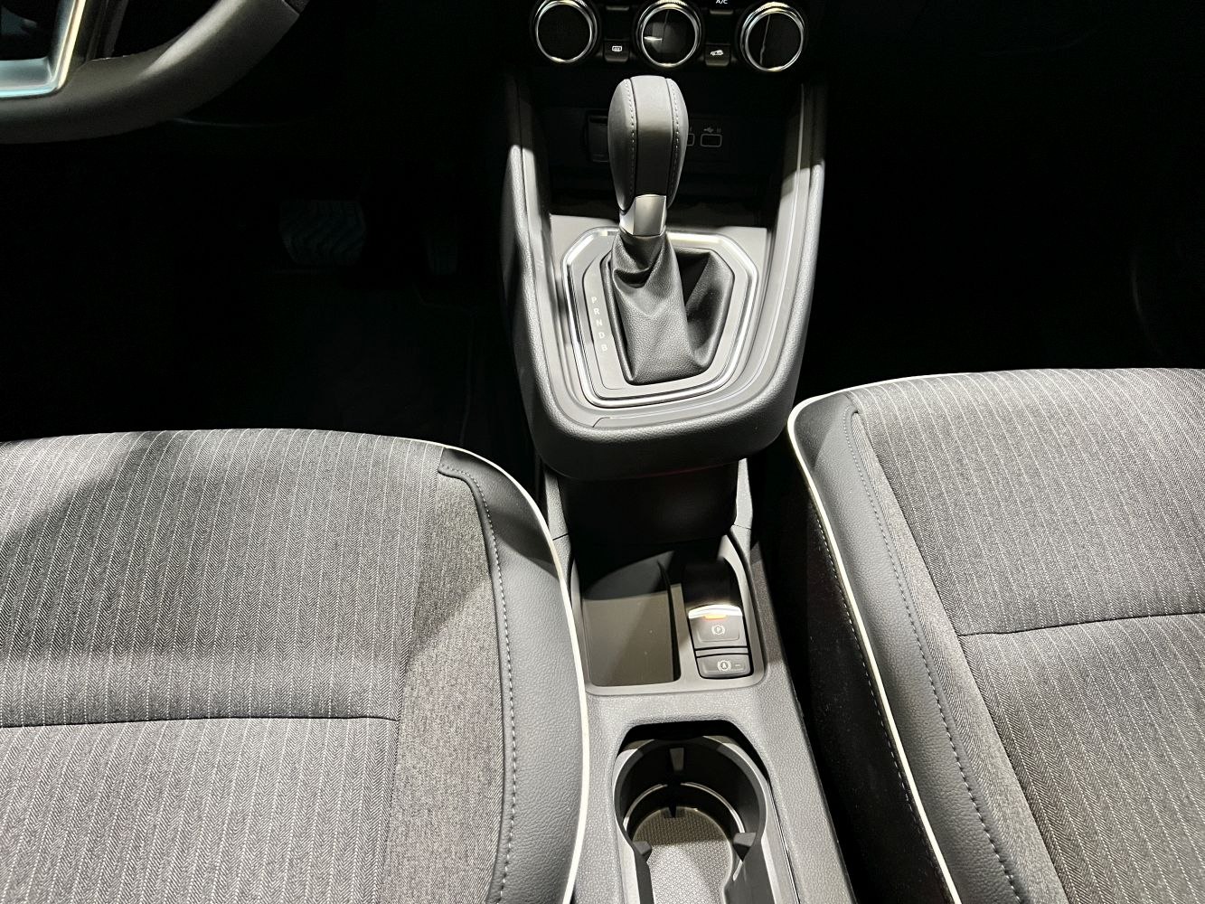Center console with gear shifter, cup holder, and fabric seats.