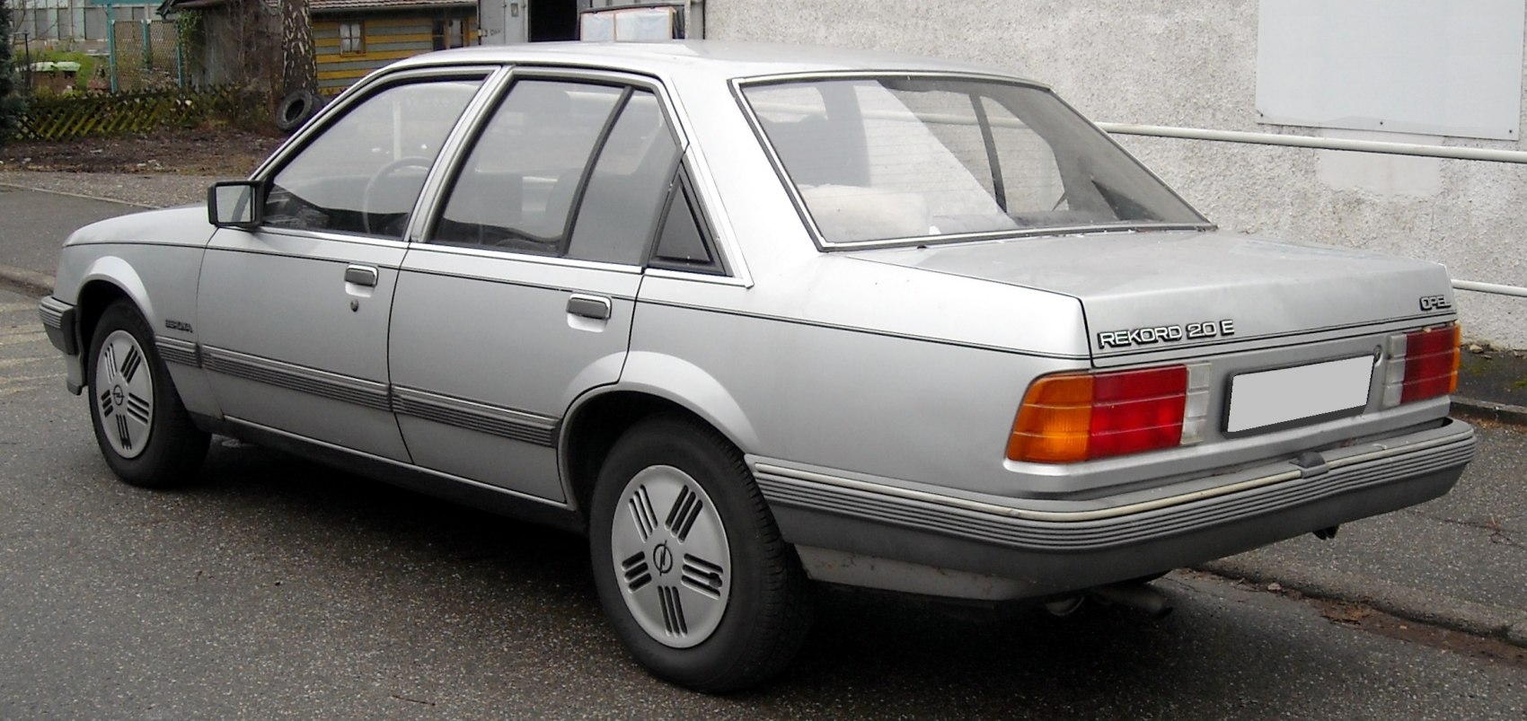 Rear side view of a classic 1980s sedan with distinct taillights and wheel covers