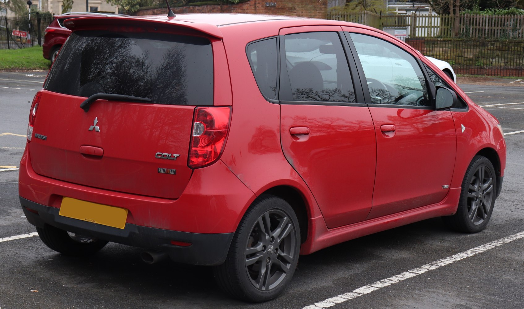 Red hatchback with black alloy wheels and rear wiper