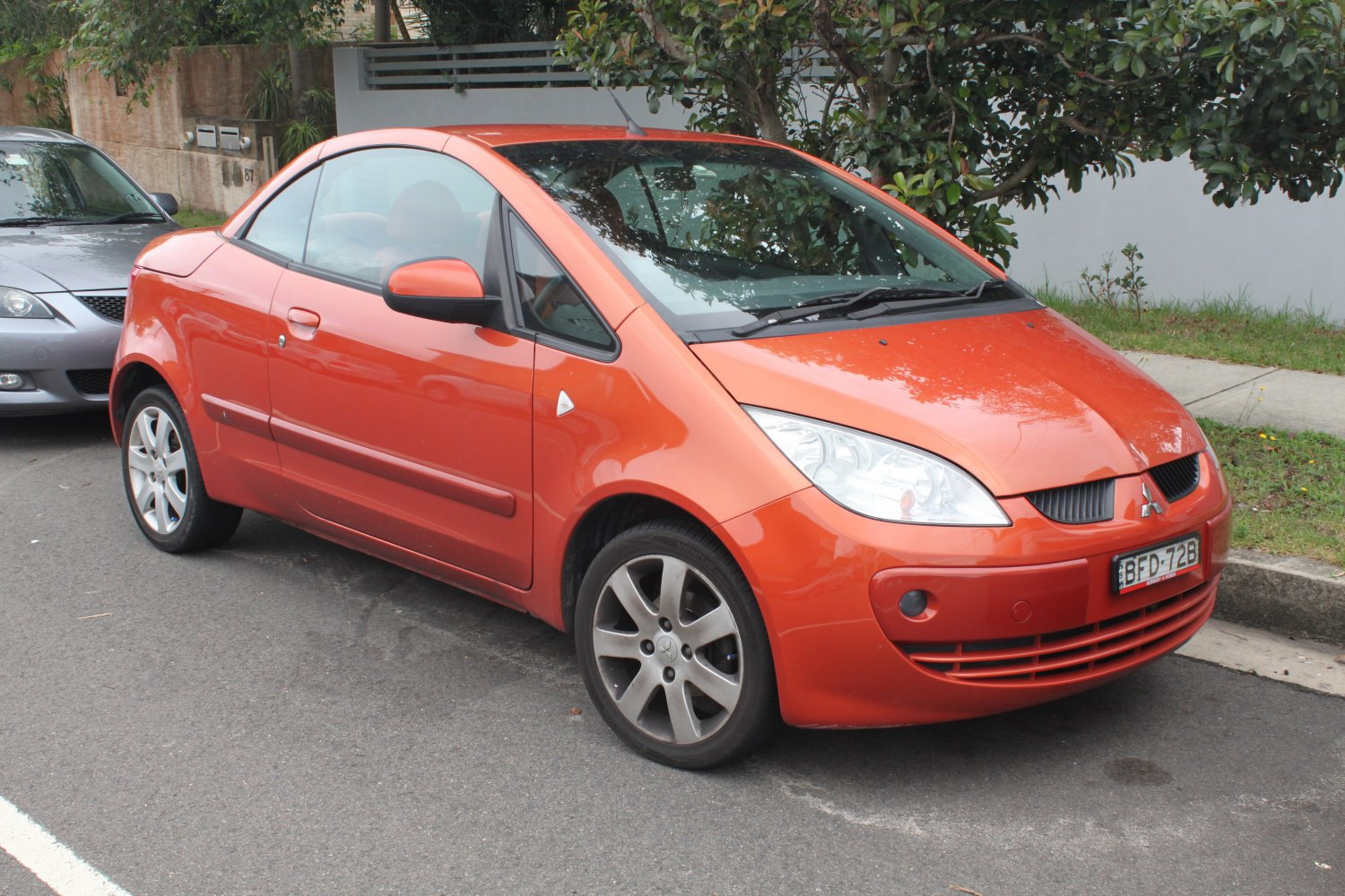 Front side view of orange compact coupe with sporty alloy wheels