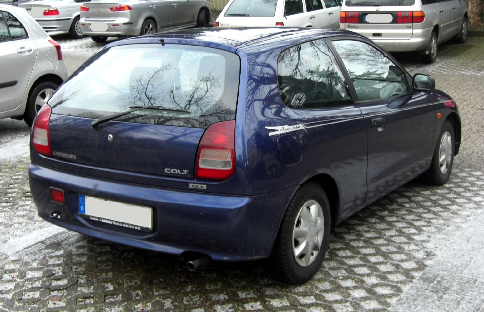 Rear view of a compact three-door hatchback with distinctive tail lights and rear windshield wiper.