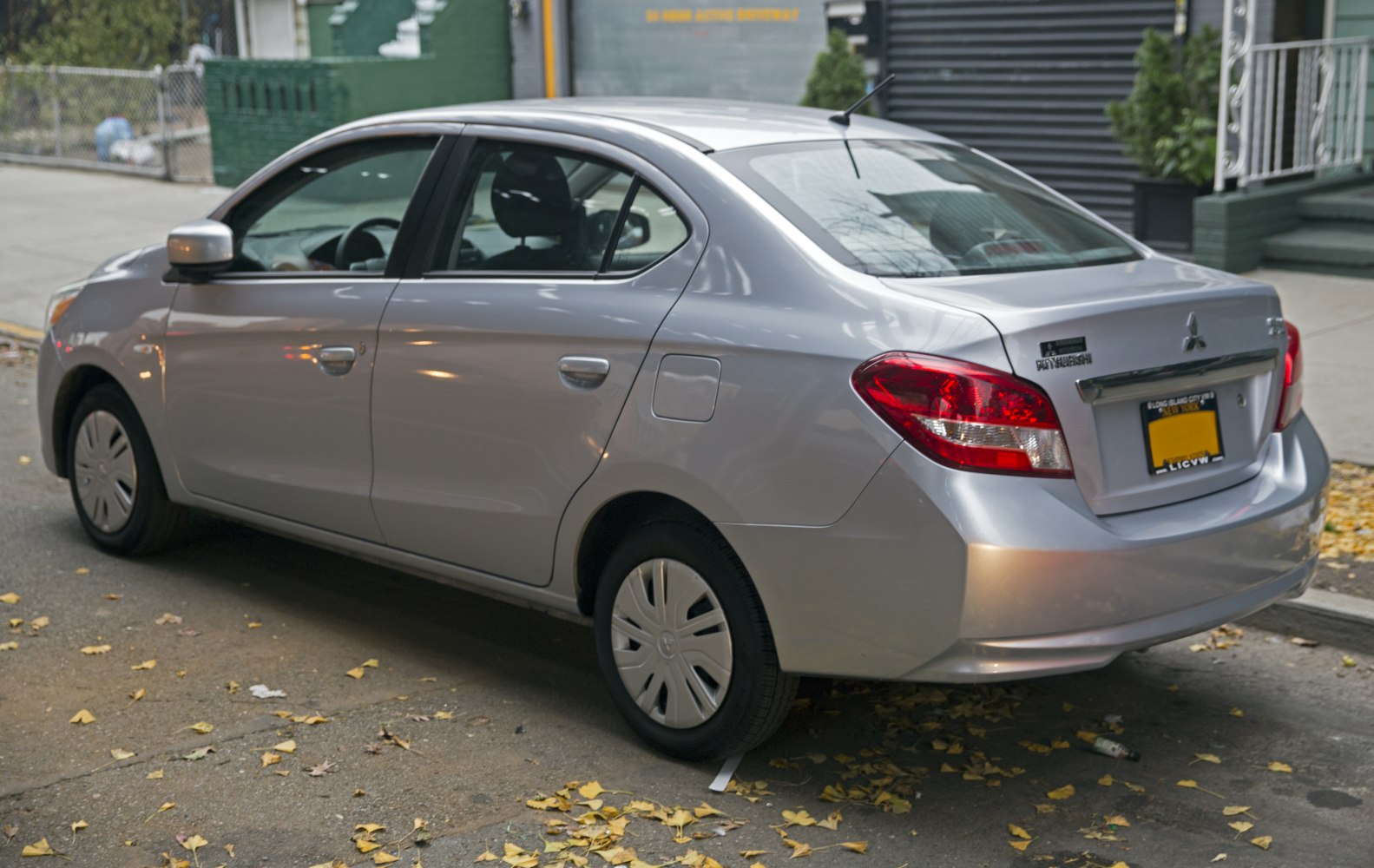 Silver compact sedan rear side view with clear tail lights and fuel door