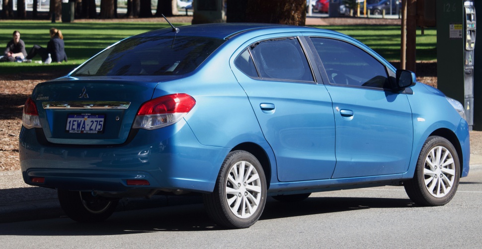 Rear side view of a blue compact sedan with distinct taillights and antenna.