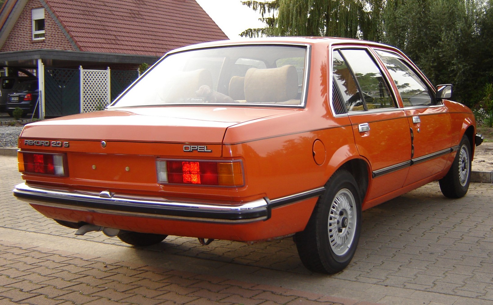 Rear and side view of classic orange sedan with retro taillights and chrome bumper
