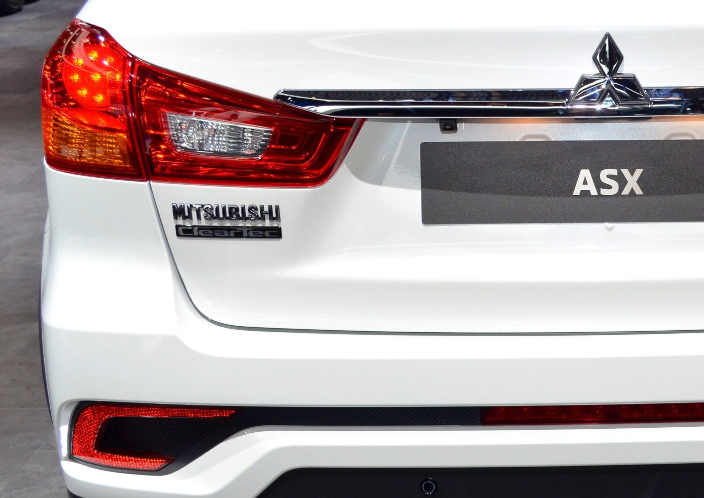 Close-up of rear light, badge, and logo on white vehicle rear