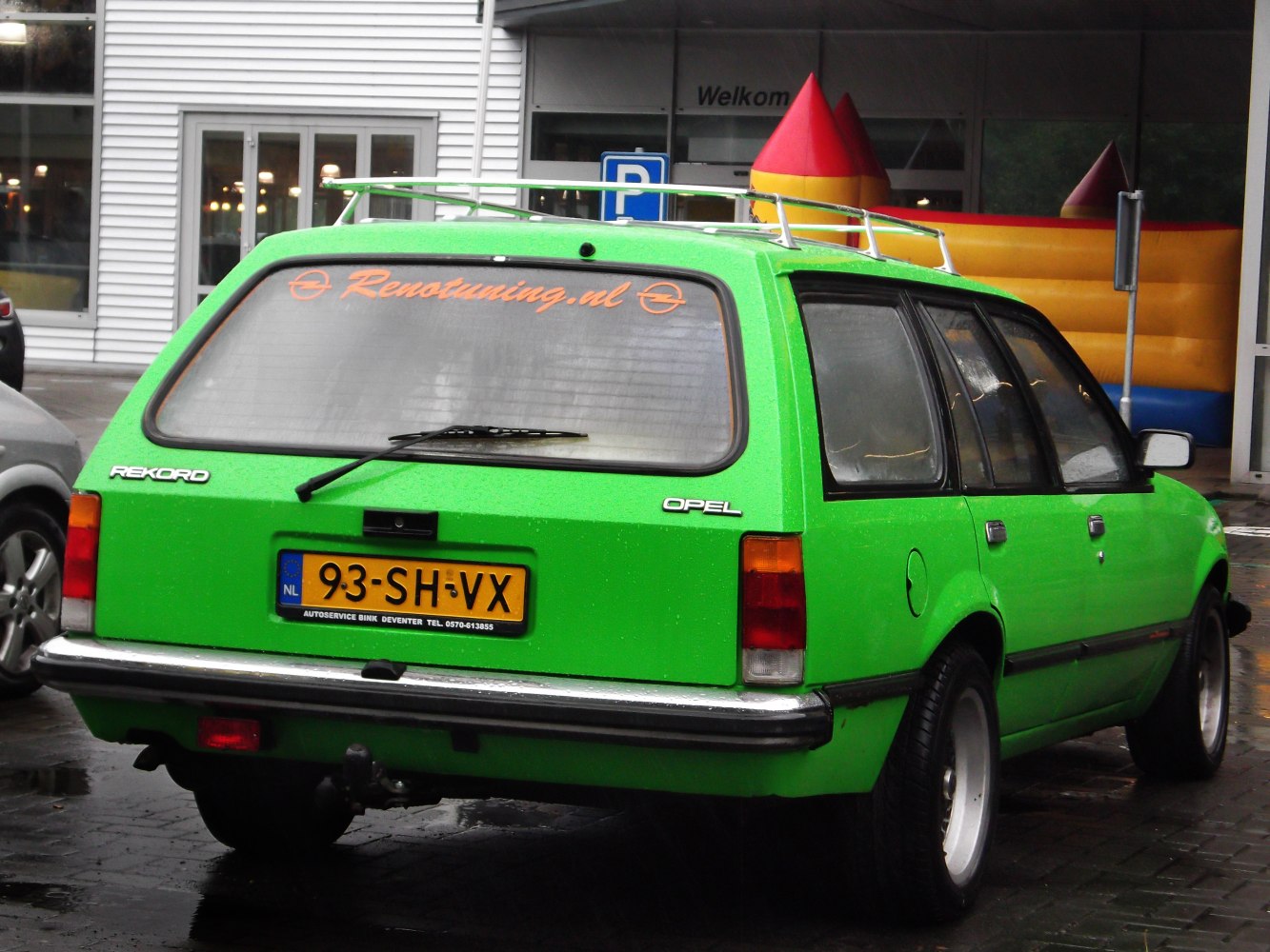 Bright green station wagon with roof rack and rear window wiper