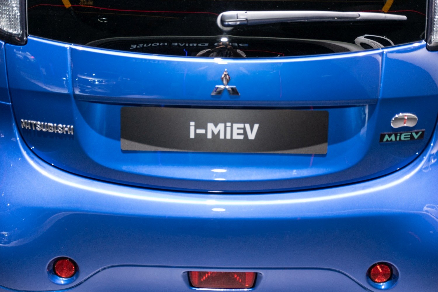 Rear close-up showing badge, emblem, and taillights of an electric vehicle.