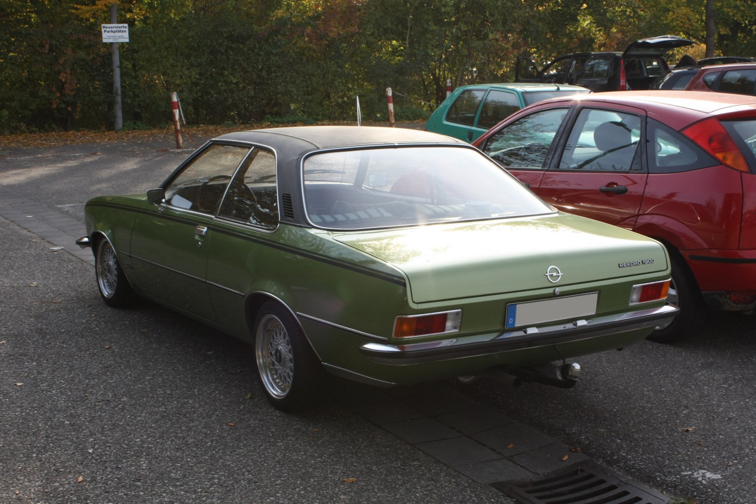 Green vintage coupe with black vinyl roof and wire wheels.