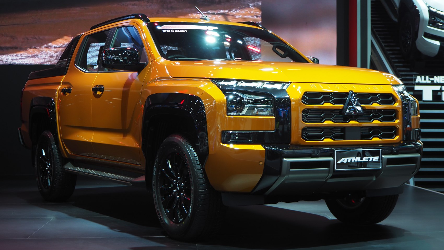 Bright orange double cab pickup with bold front grille and black wheels.