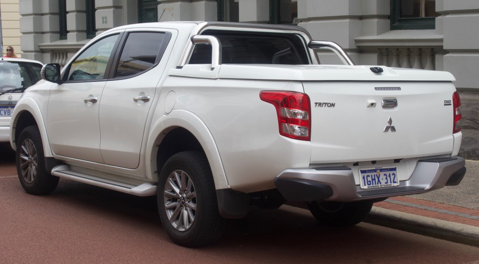 White pickup with double cab, hard tonneau cover, visible rear tailgate and alloy wheels