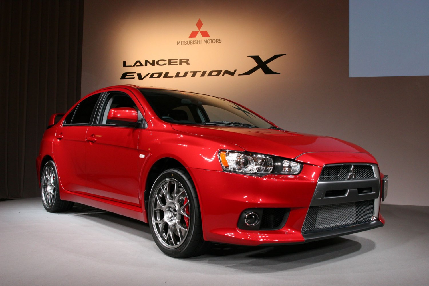 Front view of red sports sedan with alloy wheels and aggressive grille