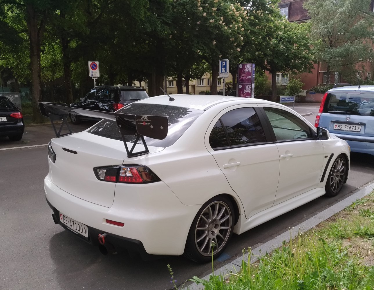 White sport sedan with large rear wing and alloy wheels