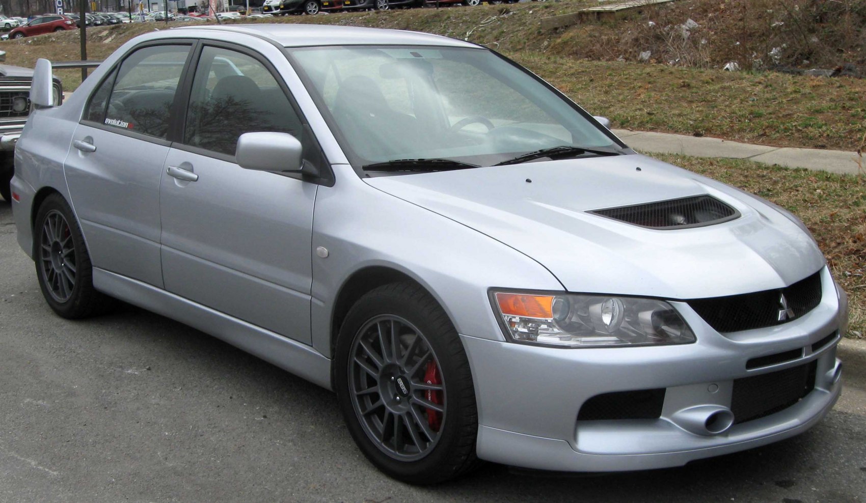Silver sedan with hood scoop and multi-spoke wheels with red brake calipers
