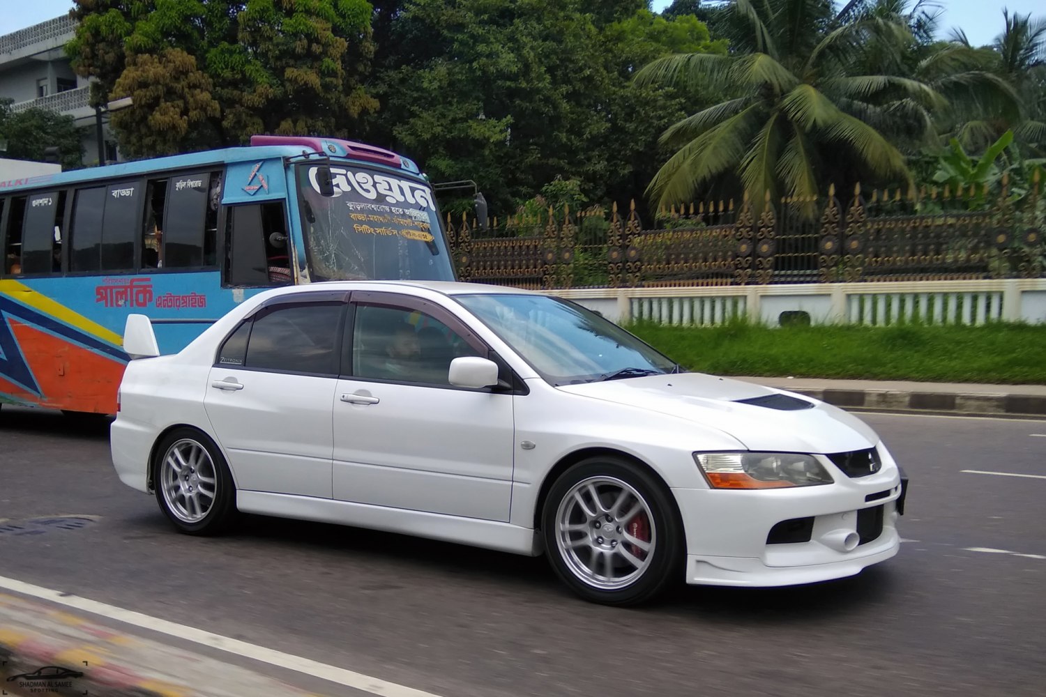 White sporty sedan with alloy wheels driving on city road