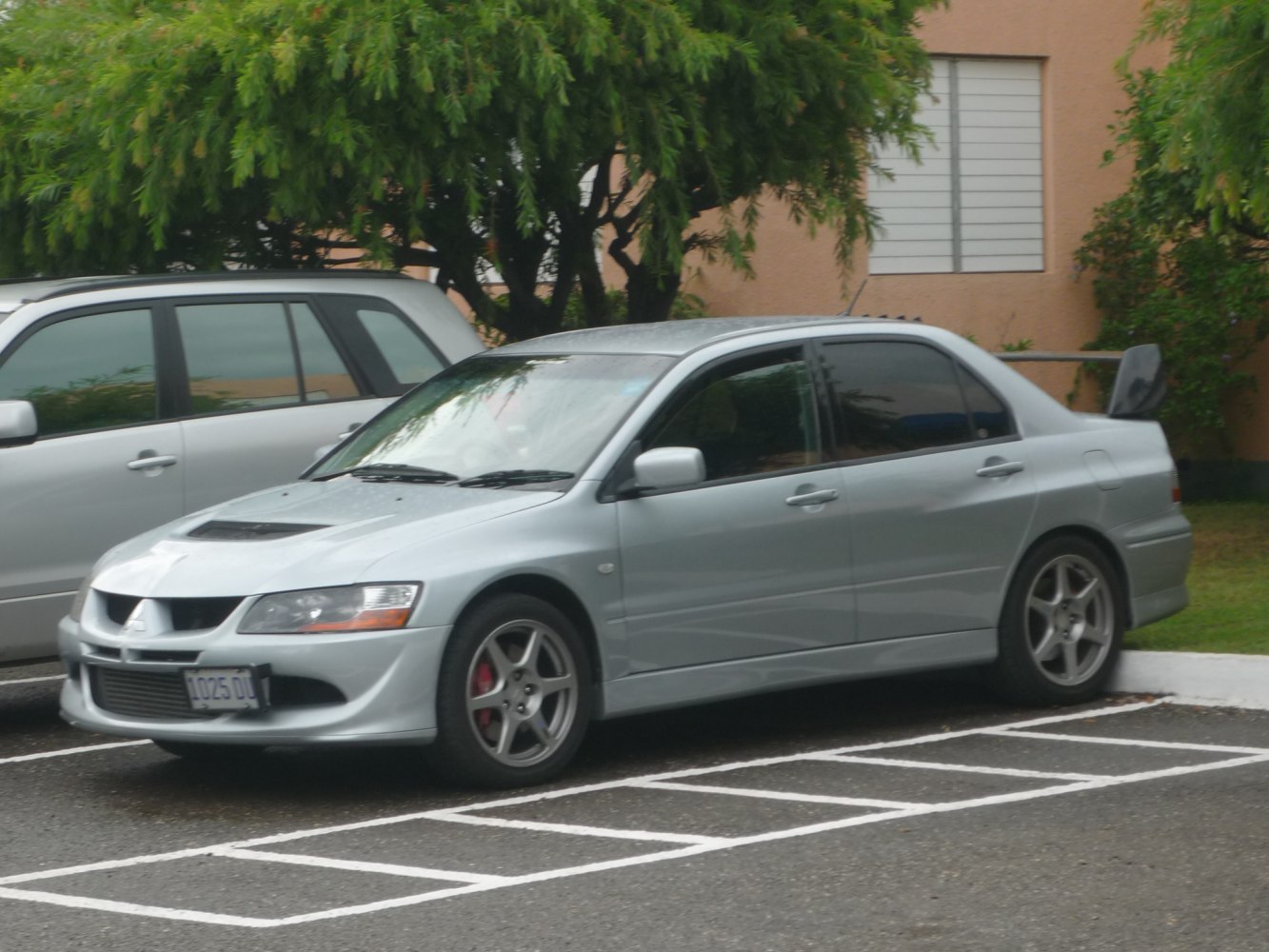 Silver sedan with large rear spoiler and front hood scoop.