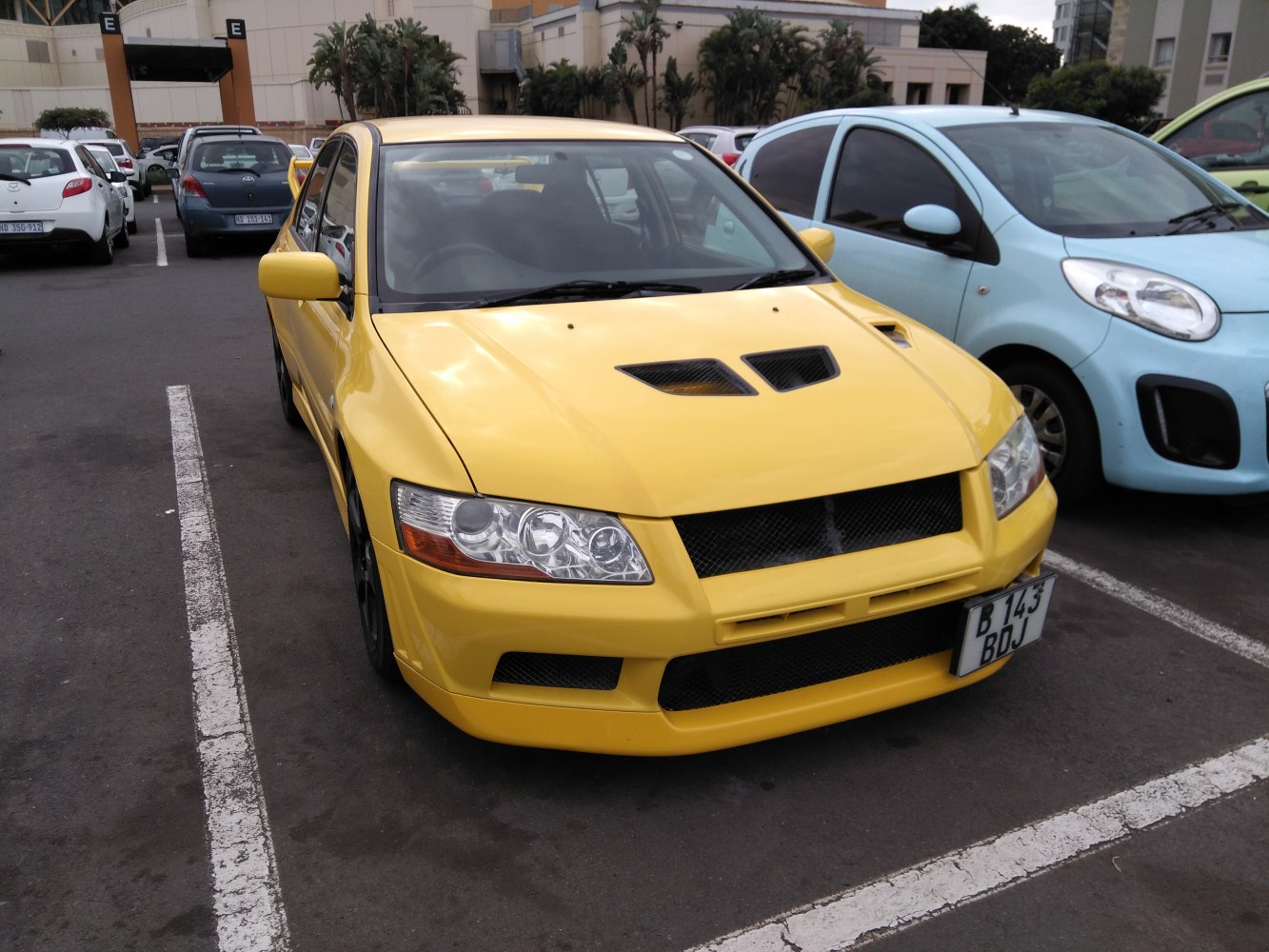 Front view of yellow sports sedan with dual hood vents and aggressive grille