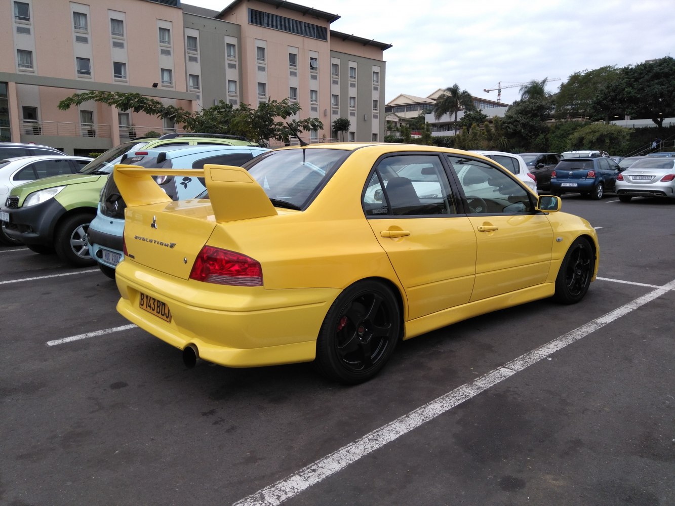 Yellow sport sedan with large rear wing and black wheels