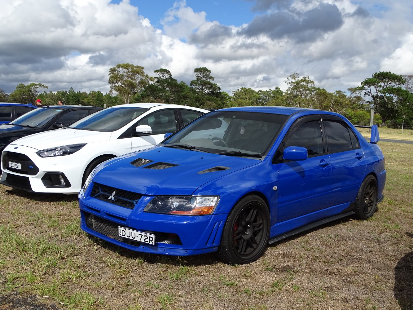 Blue sports sedan with hood vents and large rear spoiler