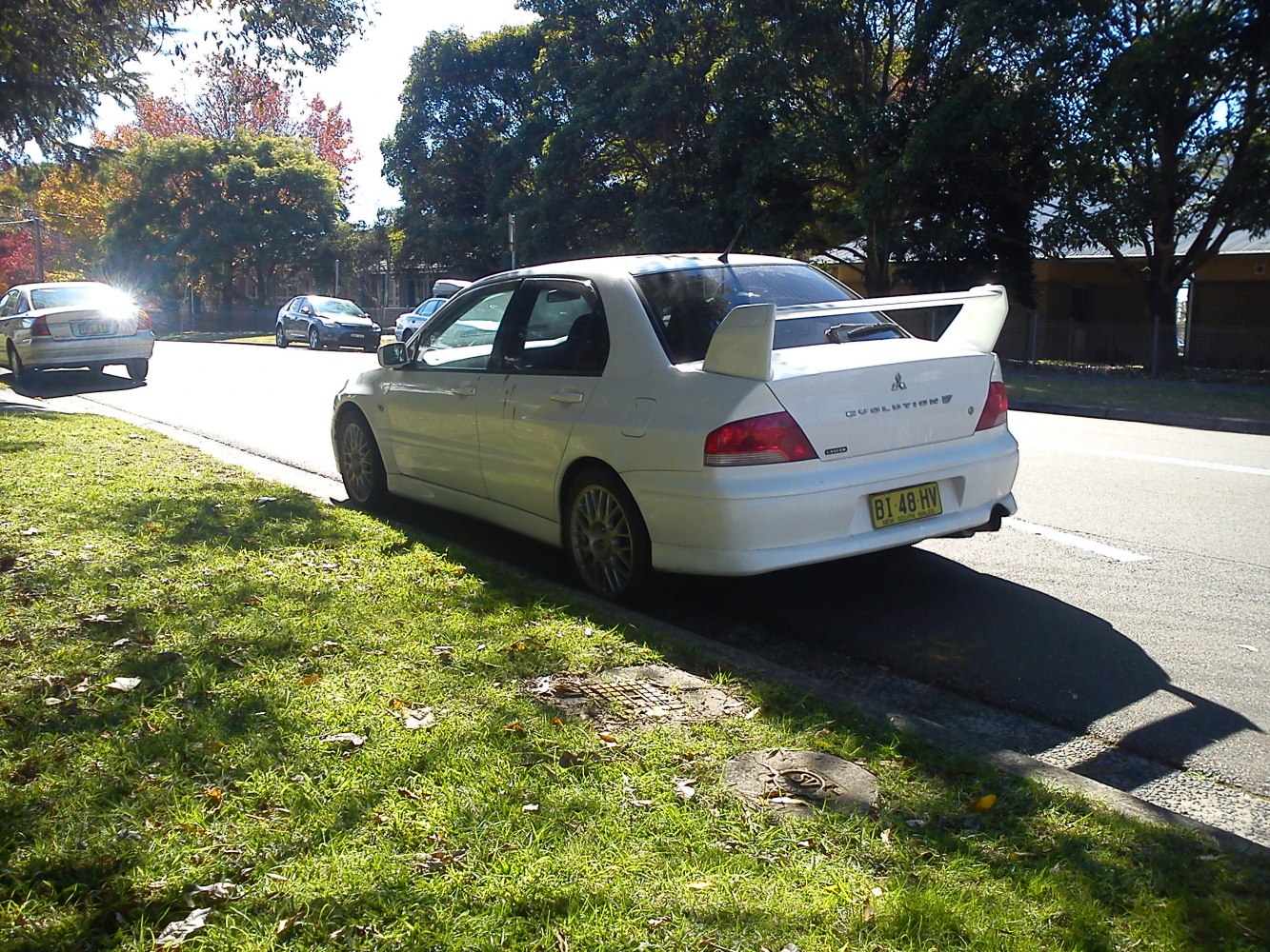 White sedan with large rear spoiler parked on street
