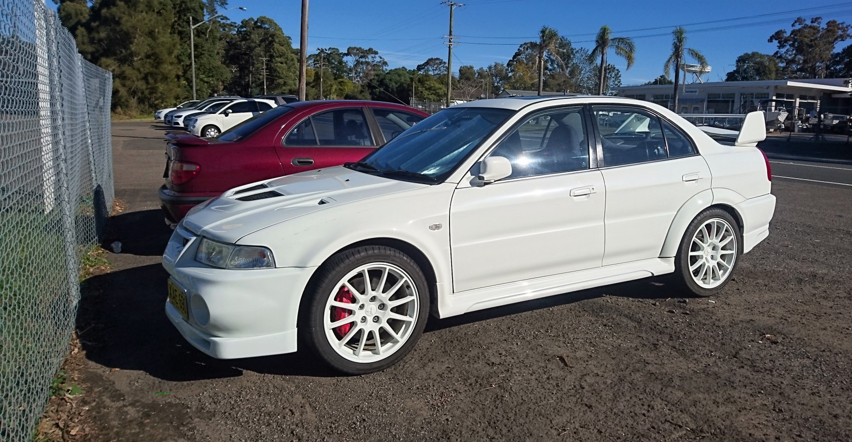 White sports sedan with front hood vents and large rear wing