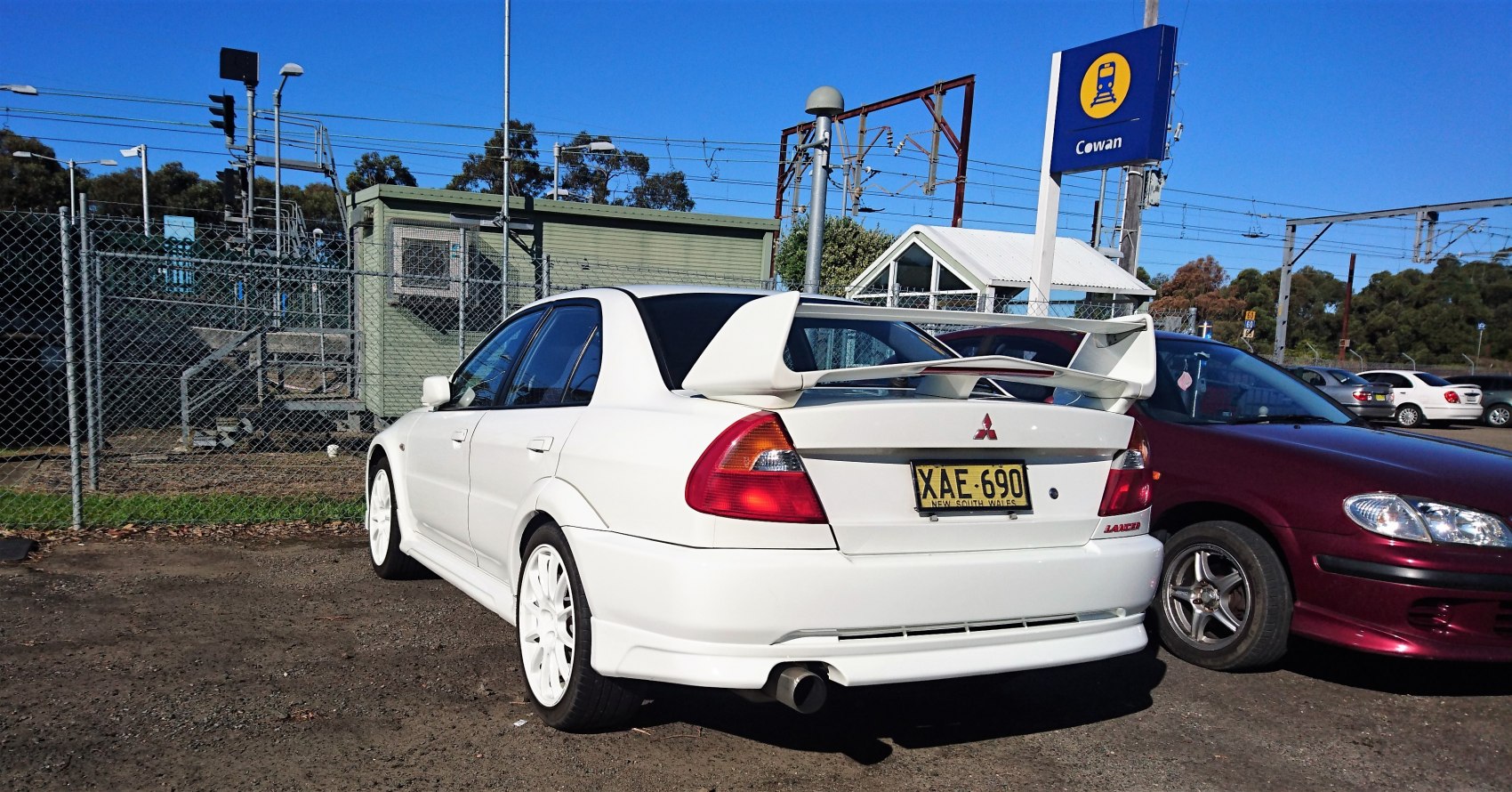White sedan with large rear wing and white rims