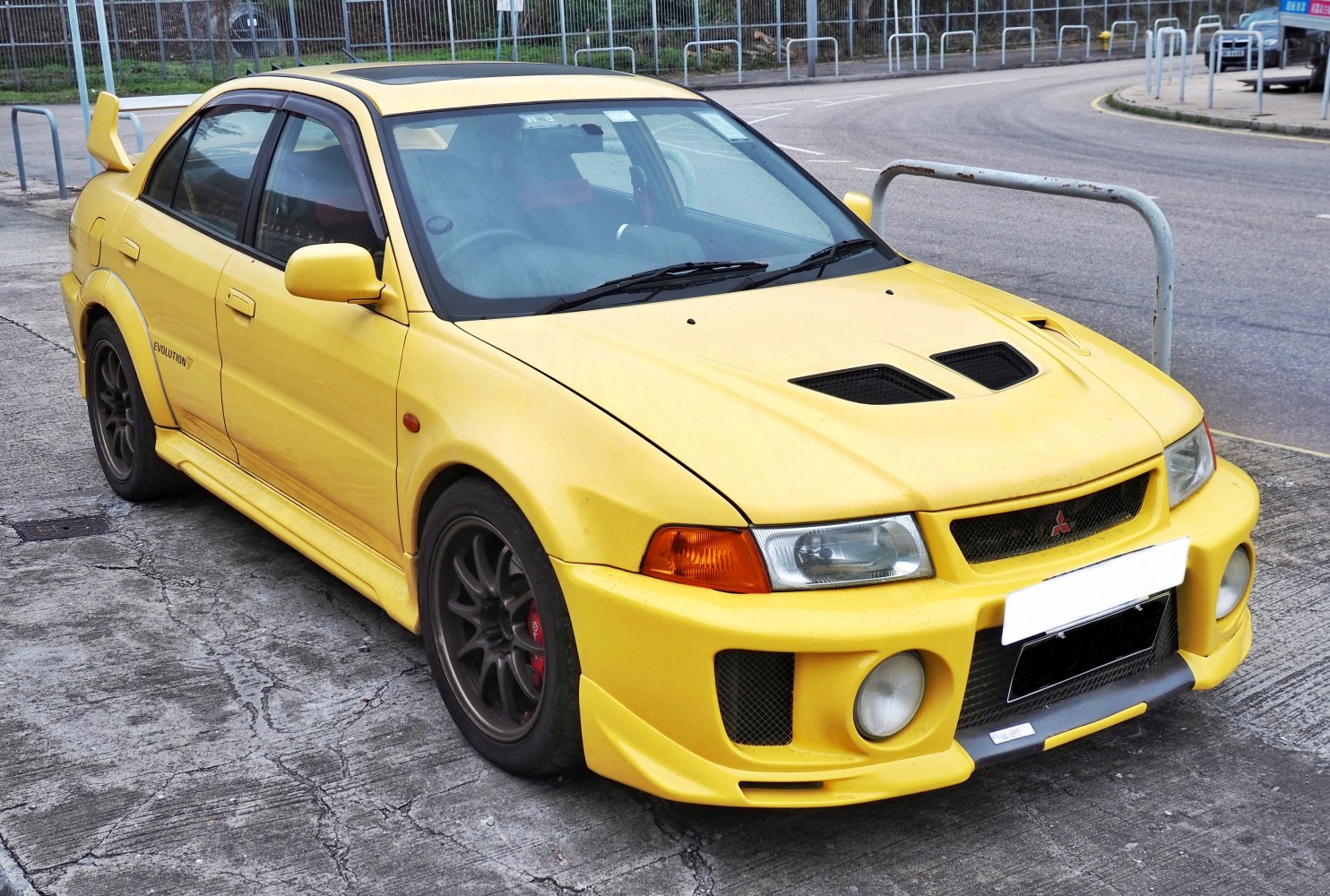 Aerodynamic yellow sports sedan with hood vents and large rear wing