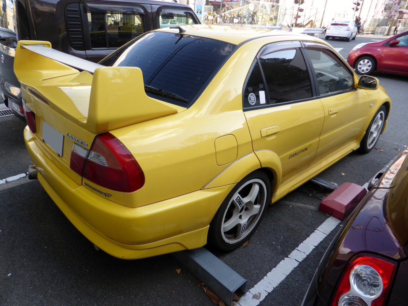 Yellow sedan with large rear wing and sporty five-spoke wheels.