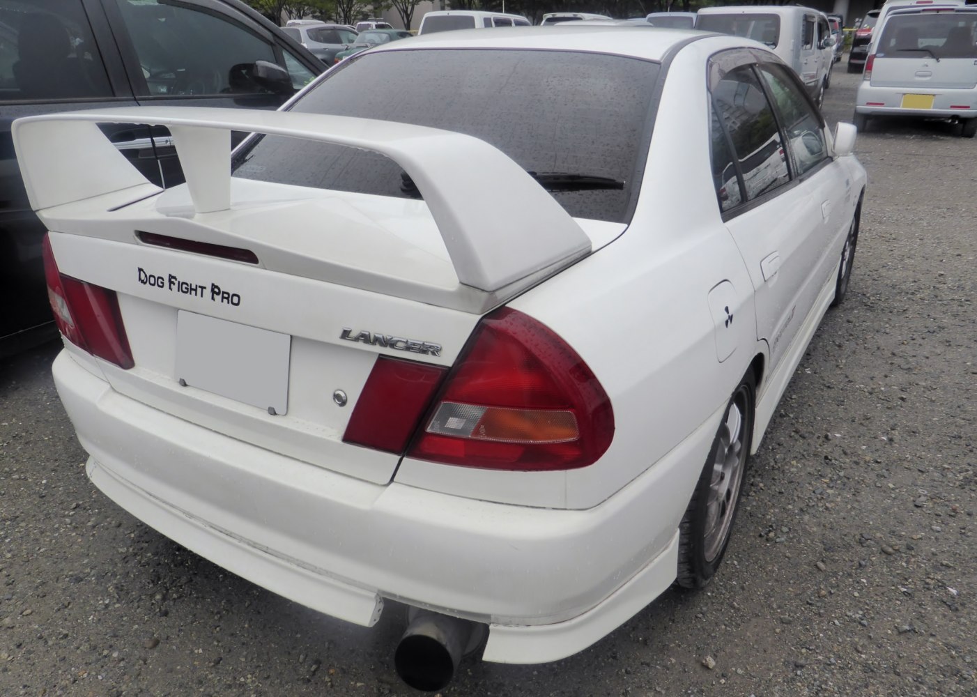 Large rear wing spoiler and big exhaust on white performance sedan rear