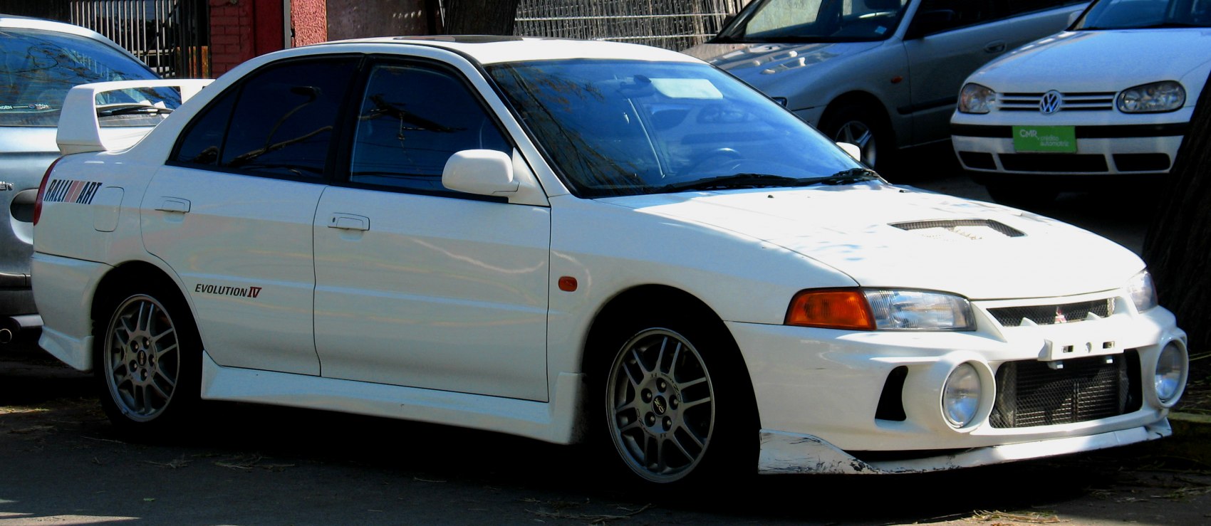 White rally-inspired sedan with hood scoop, large rear spoiler, and front fog lights