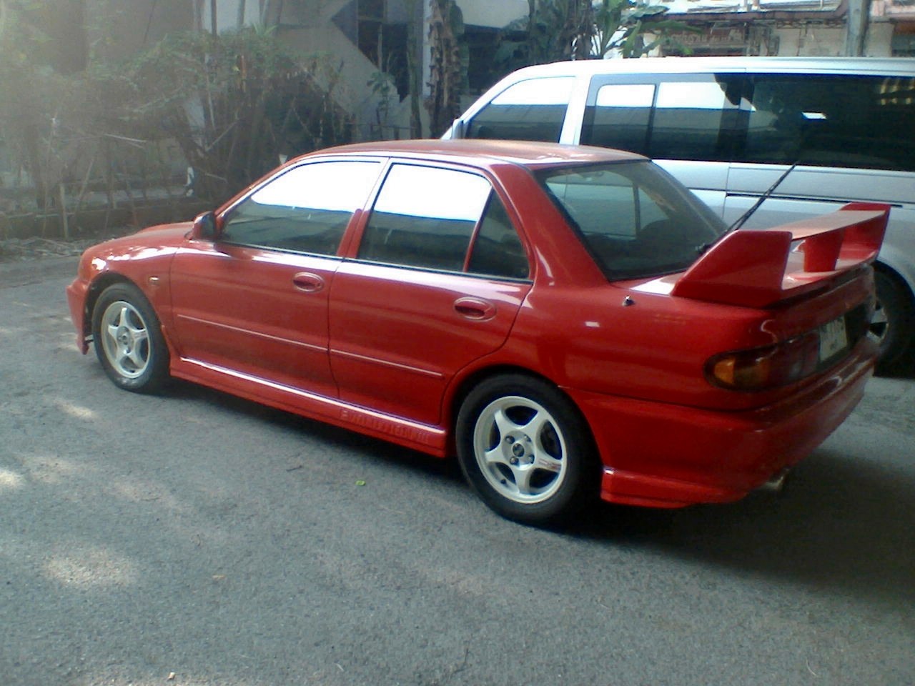 Red 4-door sedan with large rear wing and alloy wheels