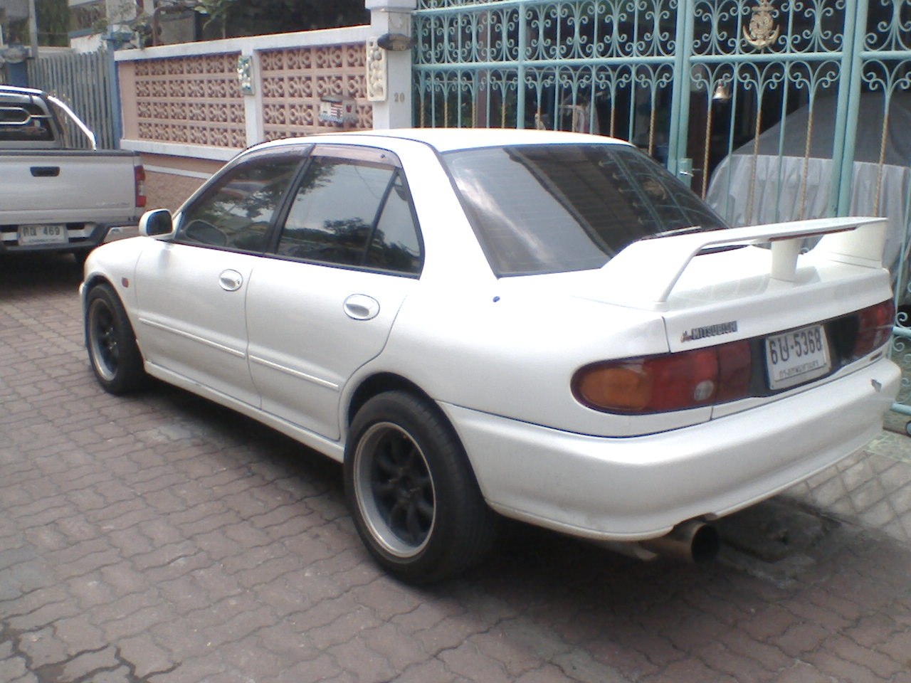 White sedan rear side view with spoiler and tinted windows