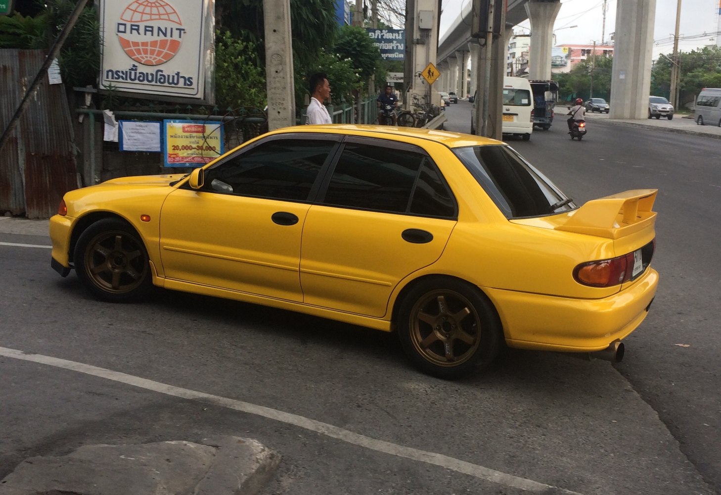 Yellow sedan with large rear spoiler and bronze alloy wheels