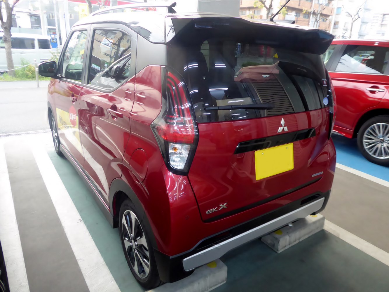 Rear and side view of a red compact car with distinctive rear lights and spoiler