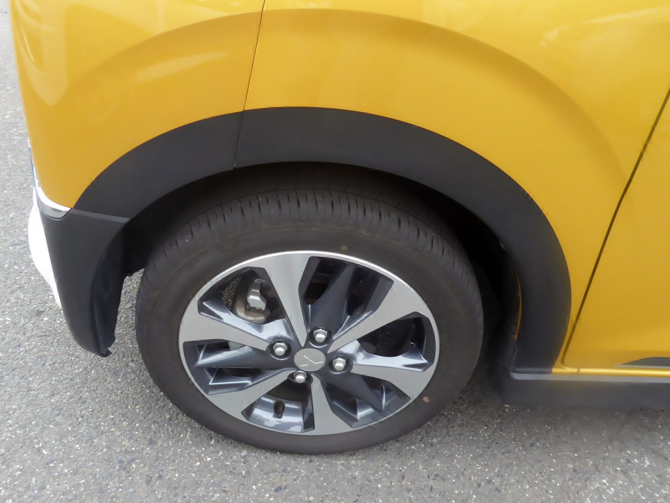 Multi-spoke alloy wheel and yellow car fender close-up
