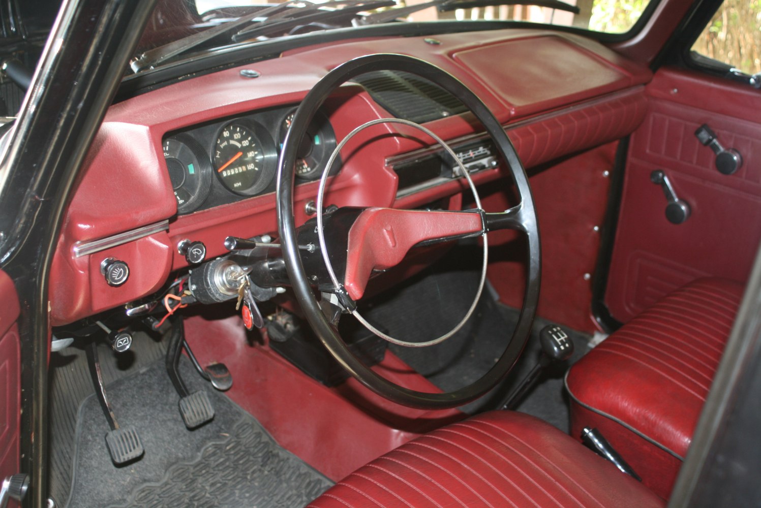 Vintage red dashboard and steering wheel with manual transmission