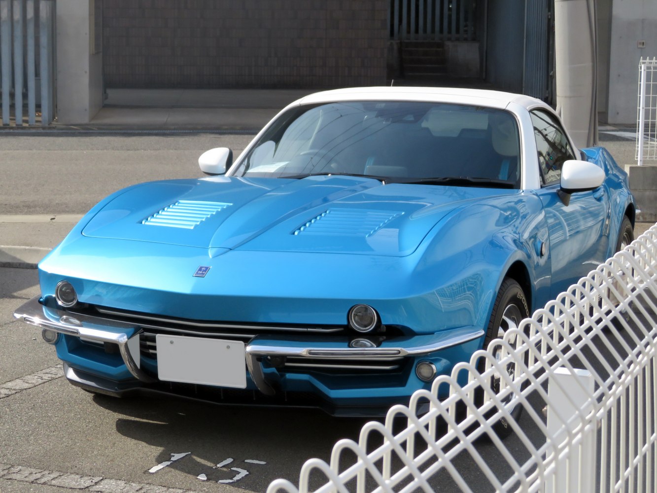Retro-styled blue sports coupe front with hood vents and chrome bumper