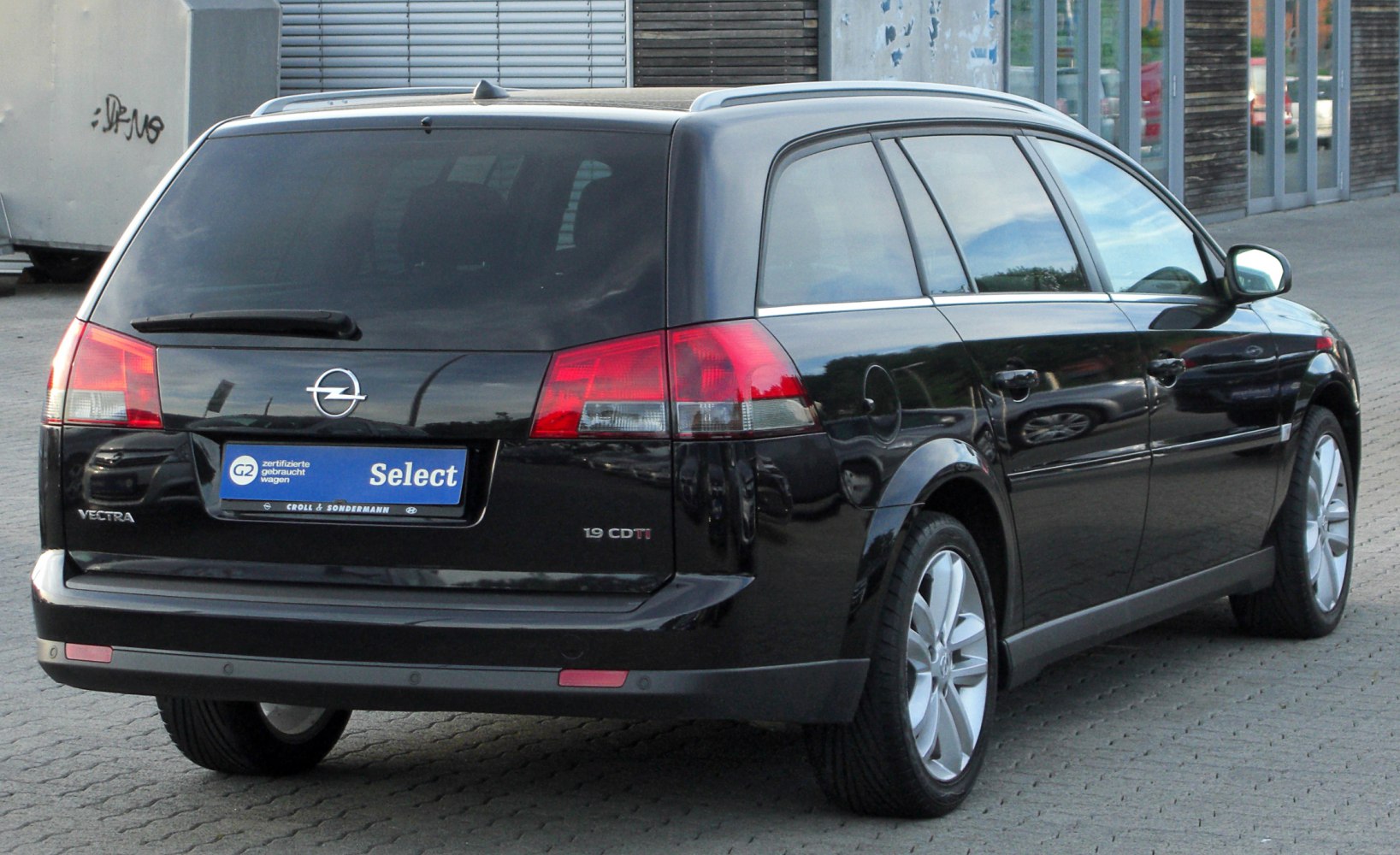 Rear view of black station wagon with taillights and tinted rear windows.