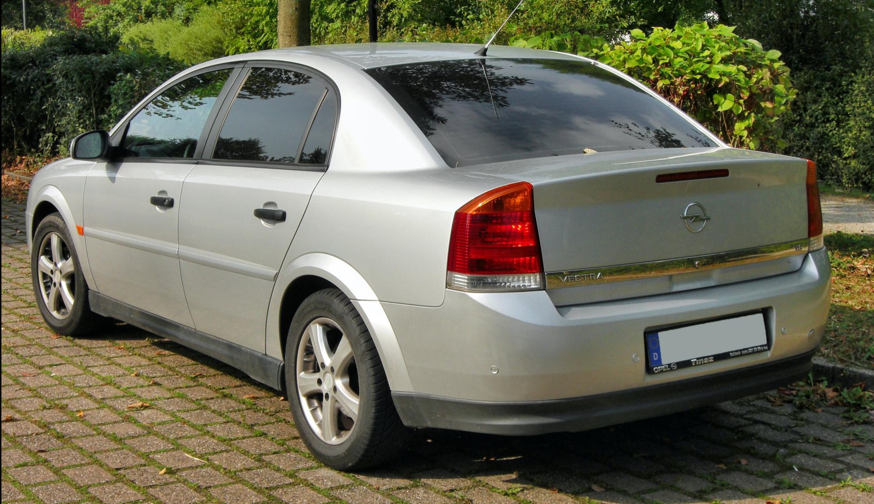 Rear and side view of silver sedan with tinted windows and alloy wheels