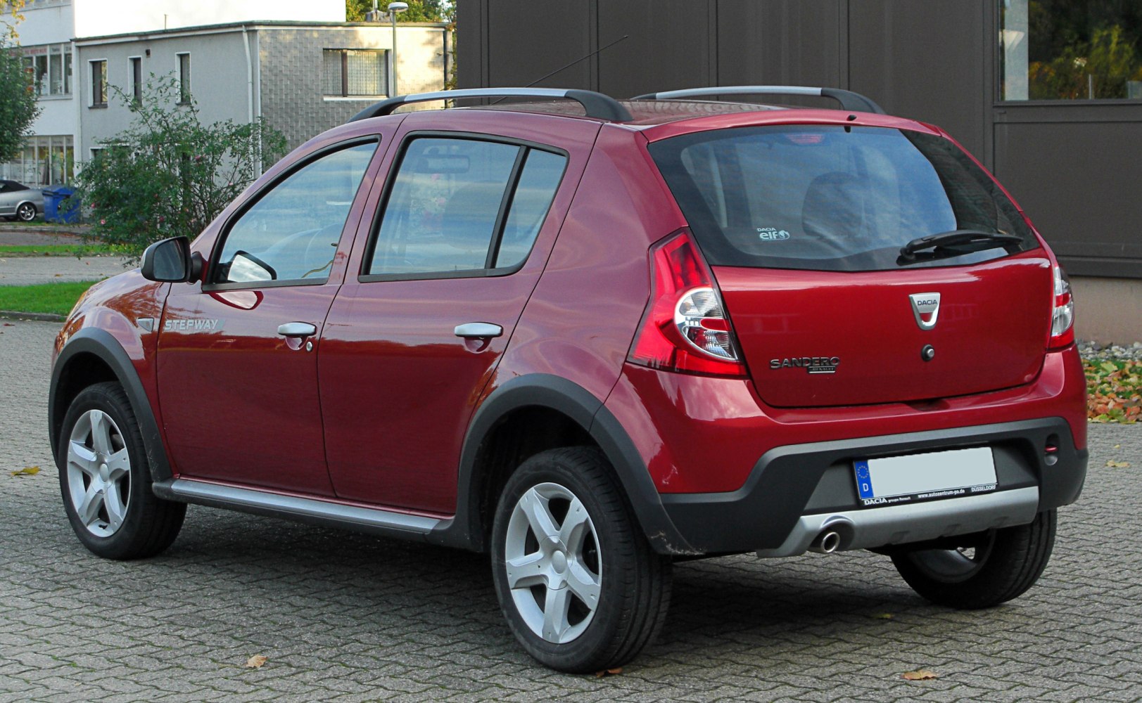 Rear angled view of red hatchback with rugged cladding and roof rails