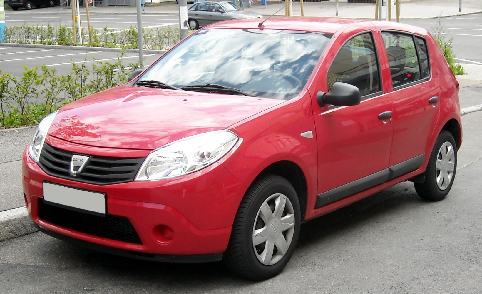Compact red hatchback with prominent headlights and black side mirrors