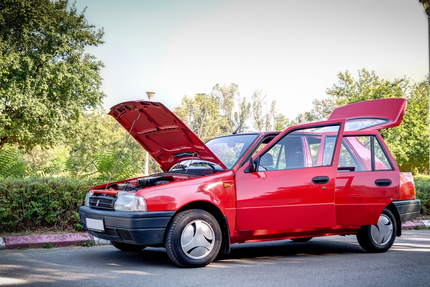 Red hatchback with open hood, door, and rear hatch